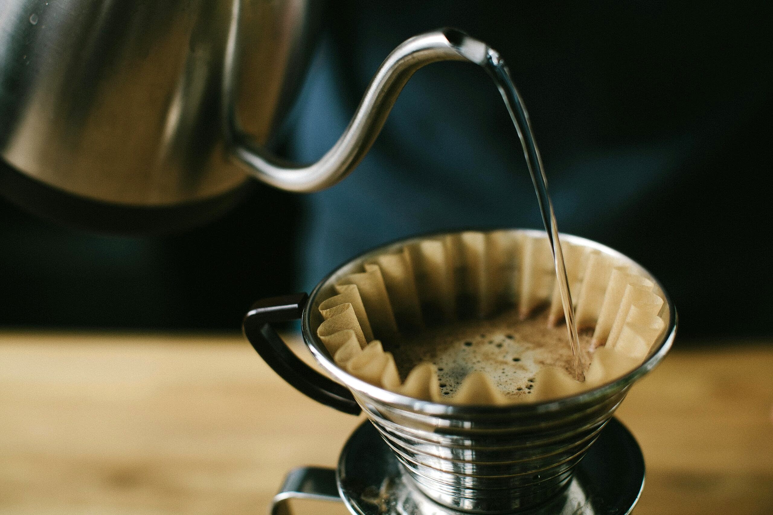 Close-up of a manual pour over coffee brewing process, highlighting the coffee and filter.